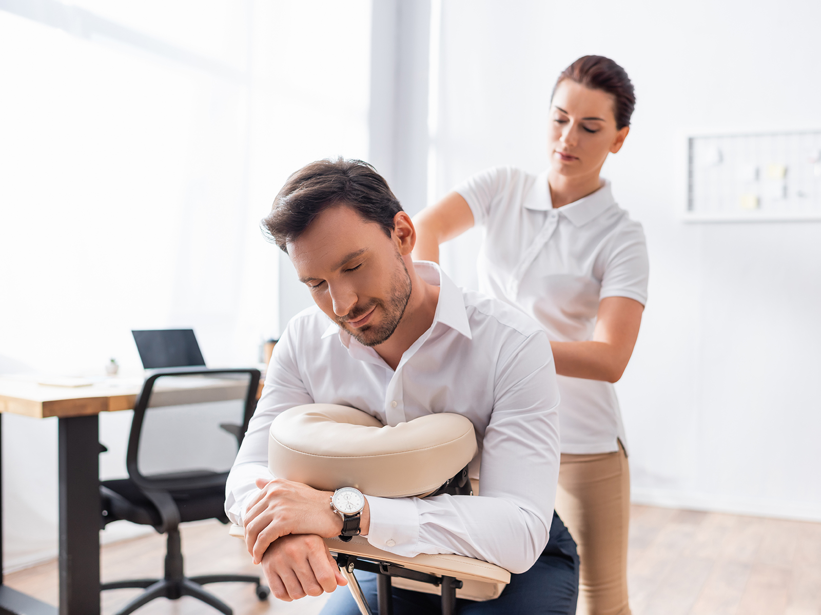 Licensed therapist providing onsite chair massage to a fully clothed office employee